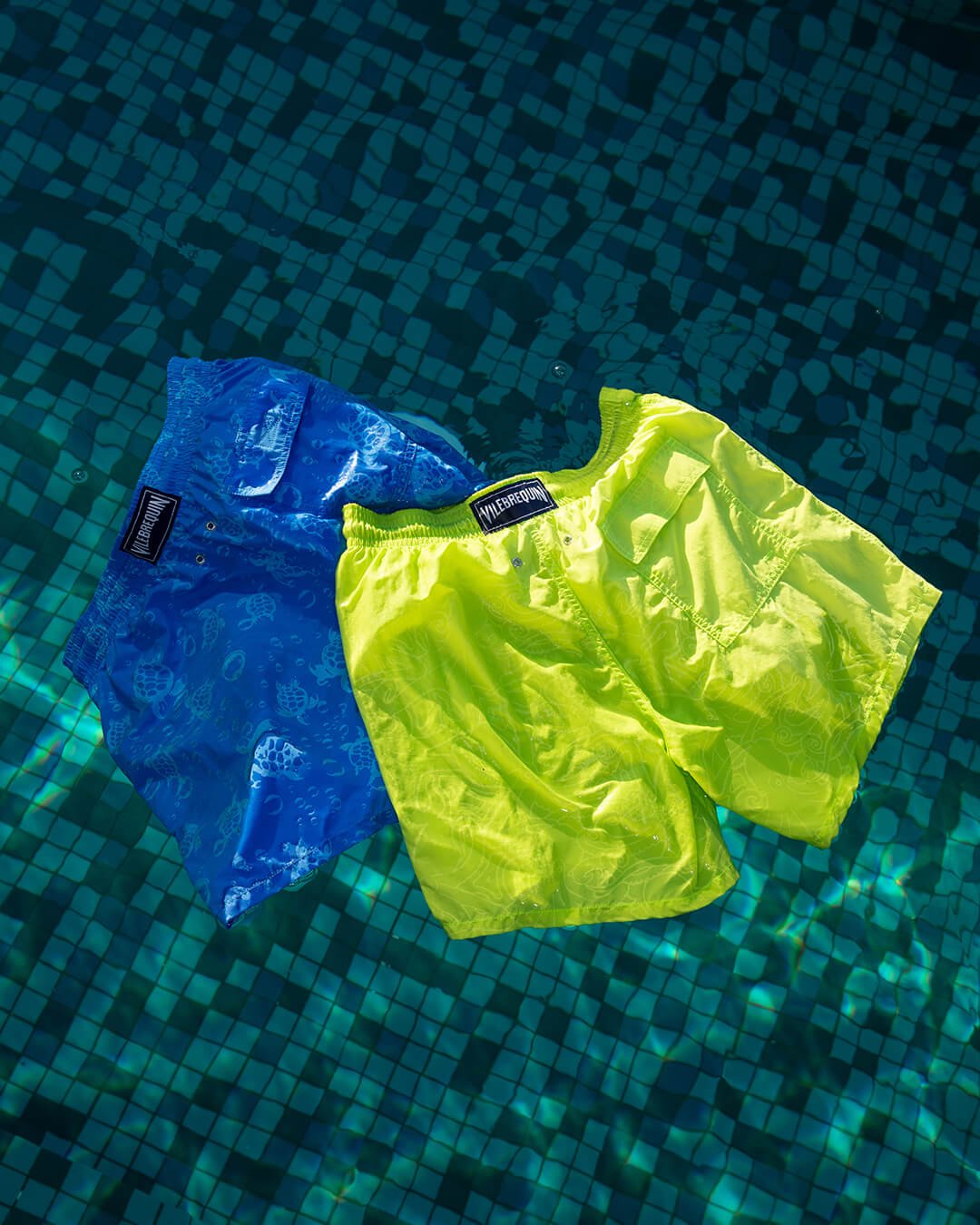 Dos trajes de baño reactivos al agua flotando en una piscina.